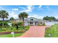 Inviting single-story home featuring a lush lawn, palm trees, and a long driveway at 3 Sea Dance Ter, Ormond Beach, FL 32176