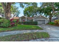 Inviting single-story home with mature landscaping, a red front door, and an attached two-car garage at 4204 Rocky Ridge Pl, Sanford, FL 32773