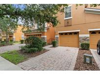 Charming two-story townhome with a well-maintained front yard, featuring a brick-paved driveway and manicured landscaping at 5060 Cypress Branch Pt, Oviedo, FL 32765