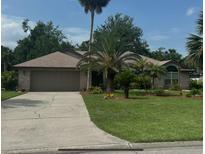 Charming brick home featuring a well-manicured lawn and mature palm trees at 6211 Oak River Ter, Port Orange, FL 32127