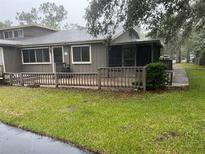 Inviting townhouse featuring a covered porch and a well-maintained, green lawn at 79 Cypress Pond Rd # 79, Port Orange, FL 32128
