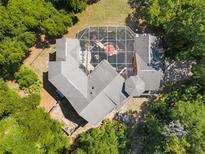 Aerial view of a large home with a screened pool, patio area, and lush surrounding trees at 4920 Sw 78Th Ave, Bushnell, FL 33513
