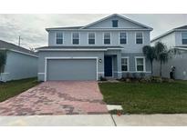 Two-story house with gray siding, brick driveway, and landscaping at 260 Crossings Ave, St Cloud, FL 34771