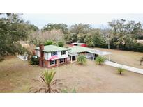 Aerial view of a two-story house with a large yard, pool, and outbuildings at 13660 Se 80Th Ave, Summerfield, FL 34491