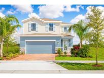 Two-story house with blue and beige exterior, brick driveway and palm trees at 5012 Balsam Falls Rd, Deland, FL 32724