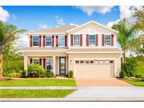 Two-story house with beige walls, red shutters, and a brick driveway at 7405 Sw 108Th St, Ocala, FL 34476