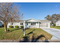 Charming single-story home with a well-manicured lawn, screened-in garage, and beautiful landscaping at 17975 Se 106Th Ct, Summerfield, FL 34491