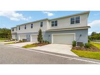 A modern townhome featuring a two-car garage, clean lines, and manicured landscaping, offering curb appeal at 6917 Five Oaks Dr, St Cloud, FL 34773