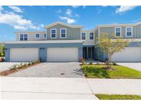Charming townhome featuring a two-car garage, blue exterior, and well-manicured landscaping at 5244 Luisa Ct, St Cloud, FL 34771