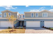 Charming townhome featuring a two-car garage, a light blue painted exterior, and manicured landscaping at 5289 Luisa Ct, St Cloud, FL 34771