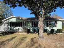 Charming single story home with light-green siding, manicured lawn, and mature shade tree in the front yard at 10867 Sw 83Rd Ct, Ocala, FL 34481