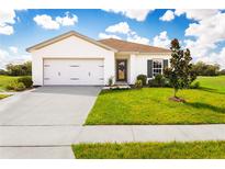 Charming one-story home boasts a manicured lawn and a two-car garage at 1365 Laramie Way, Haines City, FL 33844