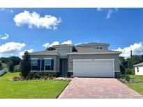 Charming single-Gathering home with a brick driveway, manicured lawn, and a two-car garage at 2088 Aibonito Cir, Clermont, FL 34711