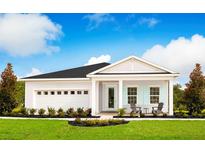 Charming single-story home with a two-car garage, front porch seating, manicured lawn and stylish light-blue shutters at 11030 Nellie Crossing Cir, Clermont, FL 34711