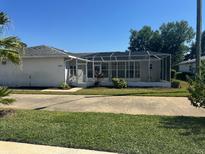 Single-story home features a screened-in lanai, complemented by manicured landscaping and a concrete driveway at 2963 Poplar Ave, Leesburg, FL 34748
