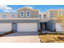 Charming townhome with blue and gray exterior, showcasing a two-car garage and manicured landscaping at 5236 Luisa Ct, St Cloud, FL 34771