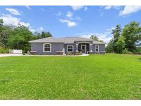 Charming single-story home featuring a well-manicured lawn and a welcoming front porch with decorative columns at 9783 Sw 206Th Court Rd, Dunnellon, FL 34431