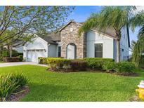 Charming home with a well-manicured lawn, stone accents, and mature landscaping creates a welcoming curb appeal at 1382 Heritage Landings Dr, Lakeland, FL 33805