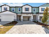Charming multi-tone two-story townhome featuring a brick driveway, covered entryway, and attached garage at 1100 Desert Candle Dr, Ocoee, FL 34761