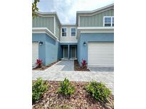 Charming townhome showcasing well-maintained landscaping, two-car garage, and inviting front entrance at 5232 Luisa Ct, St Cloud, FL 34771