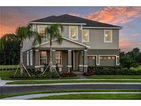 Two-story home with a charming front porch, stone accents, manicured landscaping, and a two-car garage at 3194 Tiger Palm Way, New Smyrna Beach, FL 32168
