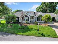Charming white brick home featuring lush landscaping and an inviting front lawn at 8596 Sw 108Th Place Rd, Ocala, FL 34481