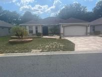 Charming single-story home with a two-car garage, flagstone driveway, landscaped yard and stucco exterior at 1424 Figueroa St, The Villages, FL 32162