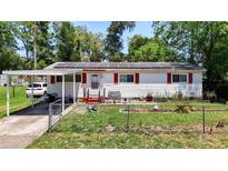 Charming single-story home with red shutters, solar panels, a carport, and fenced front yard at 801 Nw 16Th Ct, Ocala, FL 34475