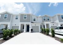 Charming townhome with white and gray exterior, attached garage, and well-maintained landscaping at 7433 Stone Creek Trl, Kissimmee, FL 34747