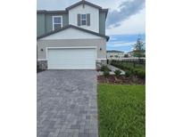 Two-story home featuring a two-car garage, stone accents, manicured lawn, and a paved driveway at 2453 Magnolia Reserve Rd, Ocoee, FL 34761