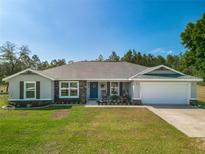 Charming single-story home with manicured lawn, stone accents, a two car garage, and inviting front porch at 12396 Sw 64Th Street Rd, Ocala, FL 34481