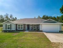 Charming single-story home featuring a well-manicured lawn and stone accents for enhanced curb appeal at 12396 Sw 64Th Street Rd, Ocala, FL 34481