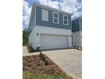 New two-story home featuring a two-car garage, manicured lawn, and a welcoming facade with blue horizontal siding at 1125 Red Buckeye Ct, Deland, FL 32720
