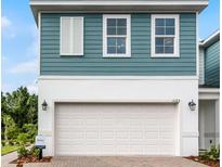 A two-story home showcasing a white garage door, white trim, teal siding, and large windows at 1125 Red Buckeye Ct, Deland, FL 32720