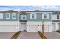 Charming townhome with a brick driveway, one-car garage, blue siding, and white trim on a sunny day at 1129 Red Buckeye Ct, Deland, FL 32720