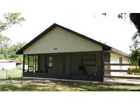 View of a screened-in porch with chairs, overlooking a grassy yard with trees at 1315 Veech Rd, Leesburg, FL 34748