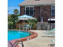 Inviting community pool with lounge chairs and umbrella-covered tables for relaxing by the water at 2200 S Palmetto Ave # E050, South Daytona, FL 32119