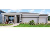 Charming single-story home featuring a three-car garage, brick accents, covered entry, and manicured lawn at 847 Emerald Grove Dr, Apopka, FL 32703