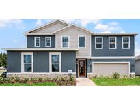 Two-story home boasts a combination of blue siding and decorative shingles at 855 Emerald Grove Dr, Apopka, FL 32703