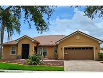 Attractive home showcasing its tile roof, well-maintained landscaping, and two-car garage with paver driveway at 3612 Northwoods Dr, Kissimmee, FL 34746
