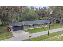 Ranch-style home featuring an attached garage, new roof, and manicured front lawn at 3207 Cr 419, Lake Panasoffkee, FL 33538