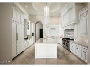 Bright kitchen features an island, white cabinetry, stone countertops and stainless appliances at 6112 E Quartz Mountain Rd, Paradise Valley, AZ 85253