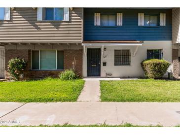Charming townhome showcasing a well-maintained front yard with a walkway to the black-colored front door at 1673 W Hazelwood St, Phoenix, AZ 85015