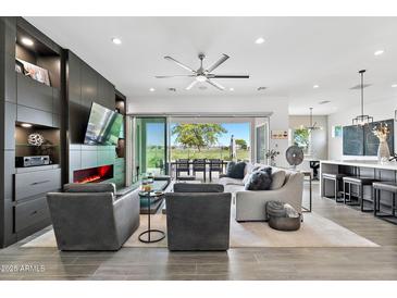 Bright living room with a modern fireplace, sleek built-ins, and a sliding glass door to the patio at 17316 W Wildwood St, Surprise, AZ 85388