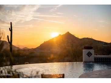 Backyard features a beautiful pool overlooking a desert landscape and a stunning orange sunset at 24724 N 119Th Pl, Scottsdale, AZ 85255