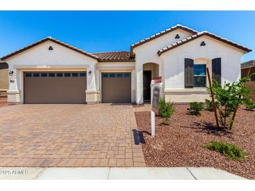 Charming single-story home featuring a brick driveway, three-car garage, and well-maintained landscaping at 20262 W Hollyhock St, Buckeye, AZ 85396