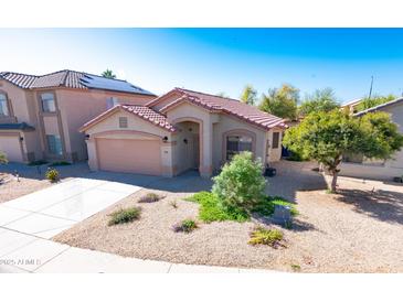 Attractive single-story home featuring a desert landscape, two-car garage, and a red tile roof under a bright blue sky at 10649 W Monte Vista Rd, Avondale, AZ 85392