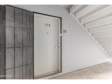 Condominium door with security screen and exterior corridor with stairs to next level at 2610 W Berridge Ln # C115, Phoenix, AZ 85017