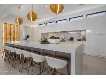 Modern kitchen with white cabinets, marble backsplash, and large island at 24863 N 103Rd N Way, Scottsdale, AZ 85255