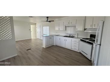 Bright kitchen features white cabinets and appliances, and an extended bar counter at 8730 E Dolega Ave, Mesa, AZ 85208